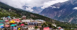 Scenic mountain village view showcasing one of the offbeat places in Himachal with colorful houses, pine forests, and misty Himalayan valleys